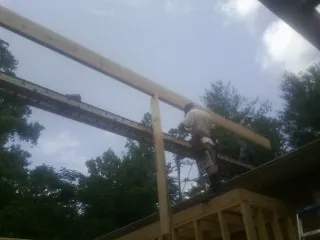 Carpenter setting a ridge beam over a new addition frame — Ice Dam Removal by Roofing Brothers in Drummond