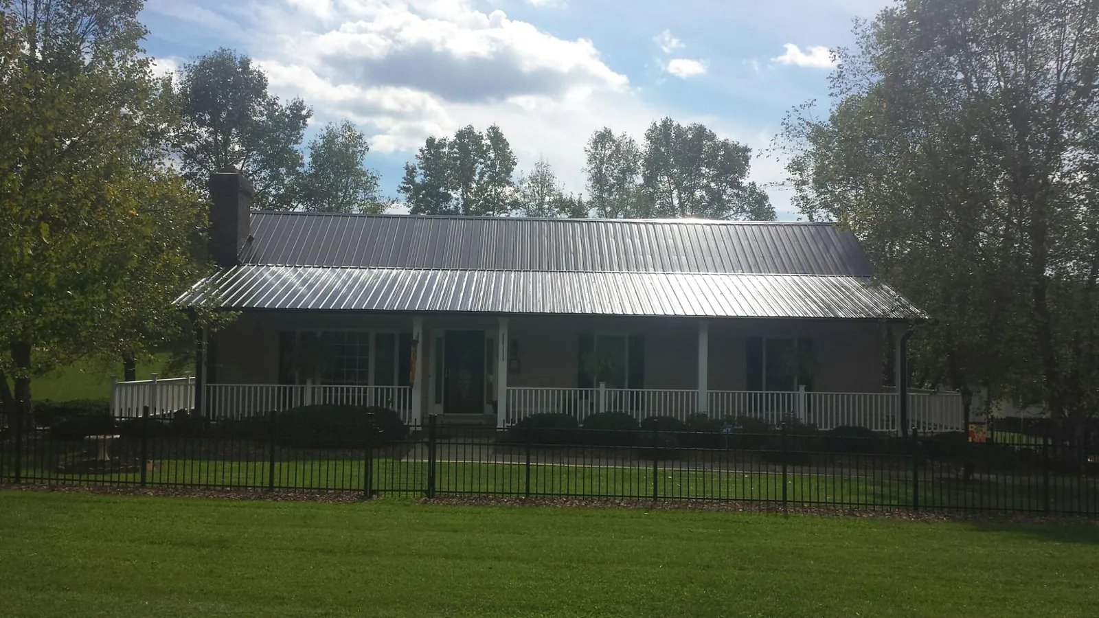 Gray metal roof on a brick ranch with a full width front porch — Gutter Guard Installation work by our crew in Drummond