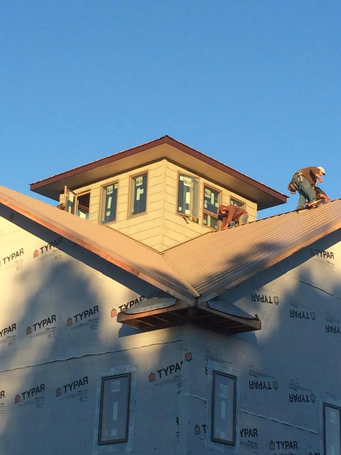 Roofers working around a rooftop cupola on a new metal roof at sunset — Roof Waterproofing in Drummond by Roofing Brothers